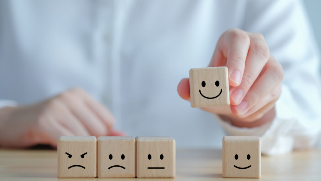 image showing blocks representing mental health by somebody picking up the block with the smiling face on it